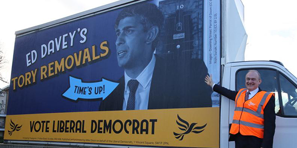 Ed Davey with a poster van reading 'Ed Davey's Removals' with a picture of Rishi Sunak and a 'Vote Liberal Democrat' banner