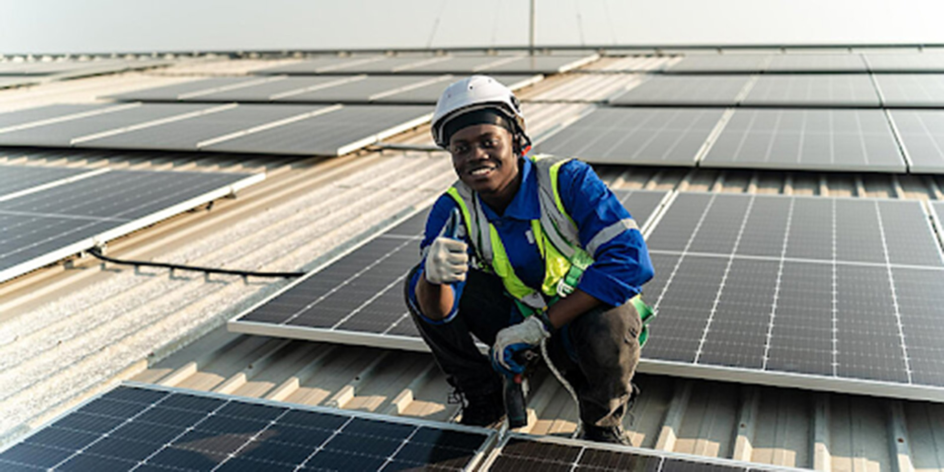 A worker on a roof full of solar panels.