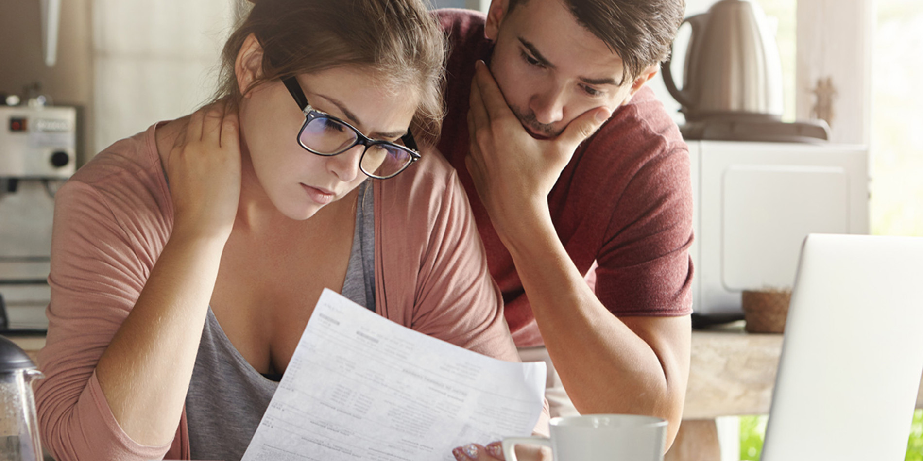 A couple look at their bills with worried faces.