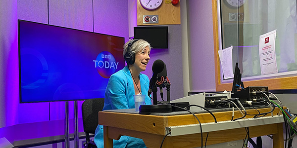 Daisy Cooper on BBC Today at a desk in a recording booth, speaking into a mic.