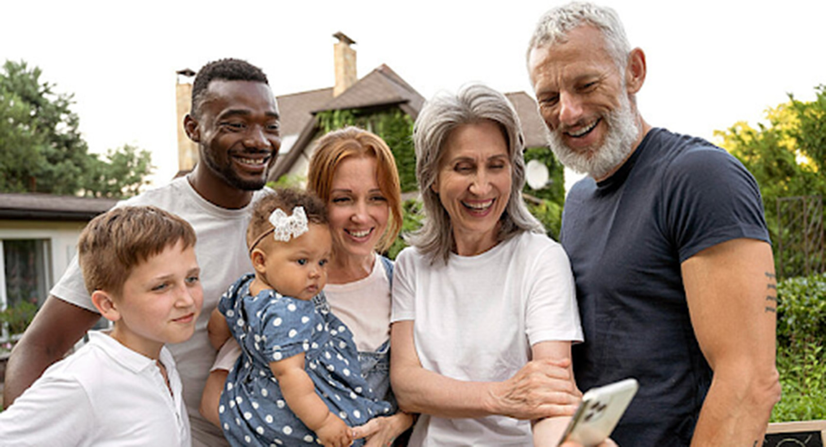 A group of people huddle together and smile into a phone screen.