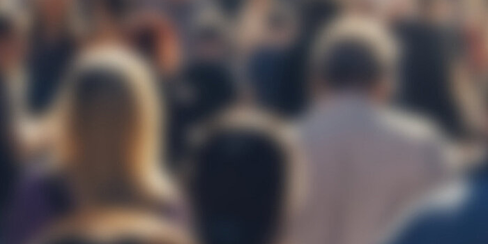 Blurred image of people standing in a crowd.