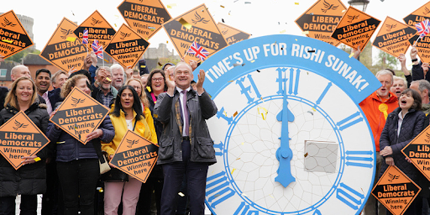 Ed Davey MP celebrates with supporters and a giant clock labelled 'Time's up for Rishi Sunak!'