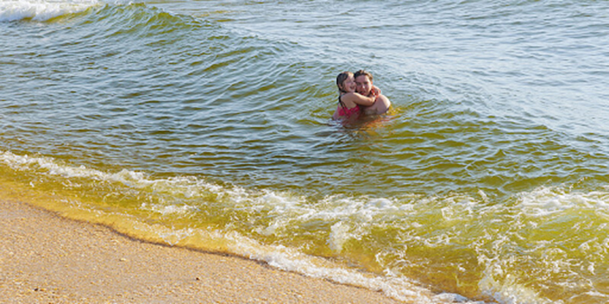 People swimming in a sea of dirty water.