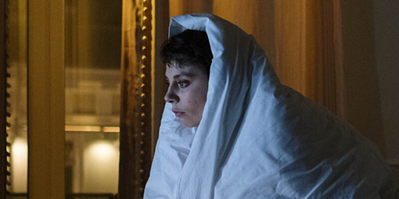A woman covers herself with a duvet.