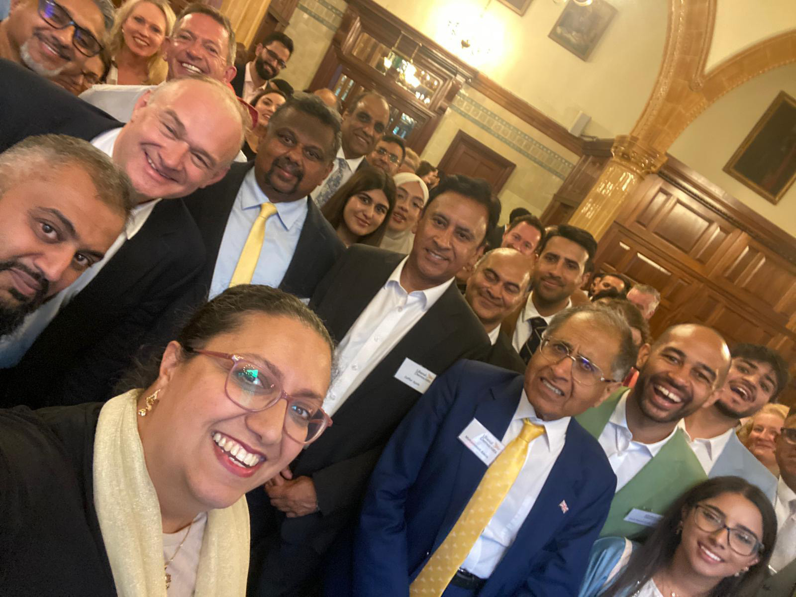 Ed Davey and Hina Bokari take a photo with a large group of people