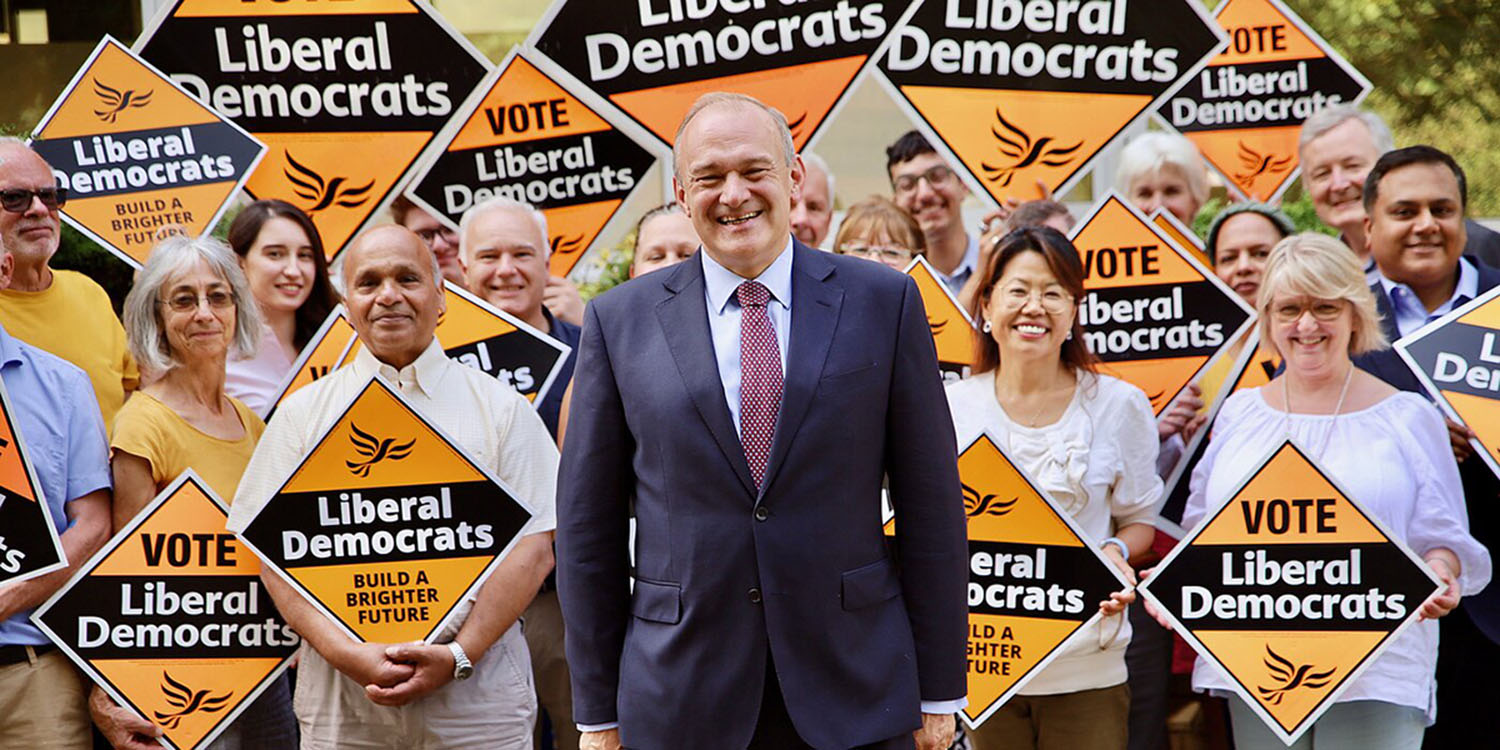 Ed Davey MP with a crowd of Lib Dem supporters holding Lib Dem diamonds.