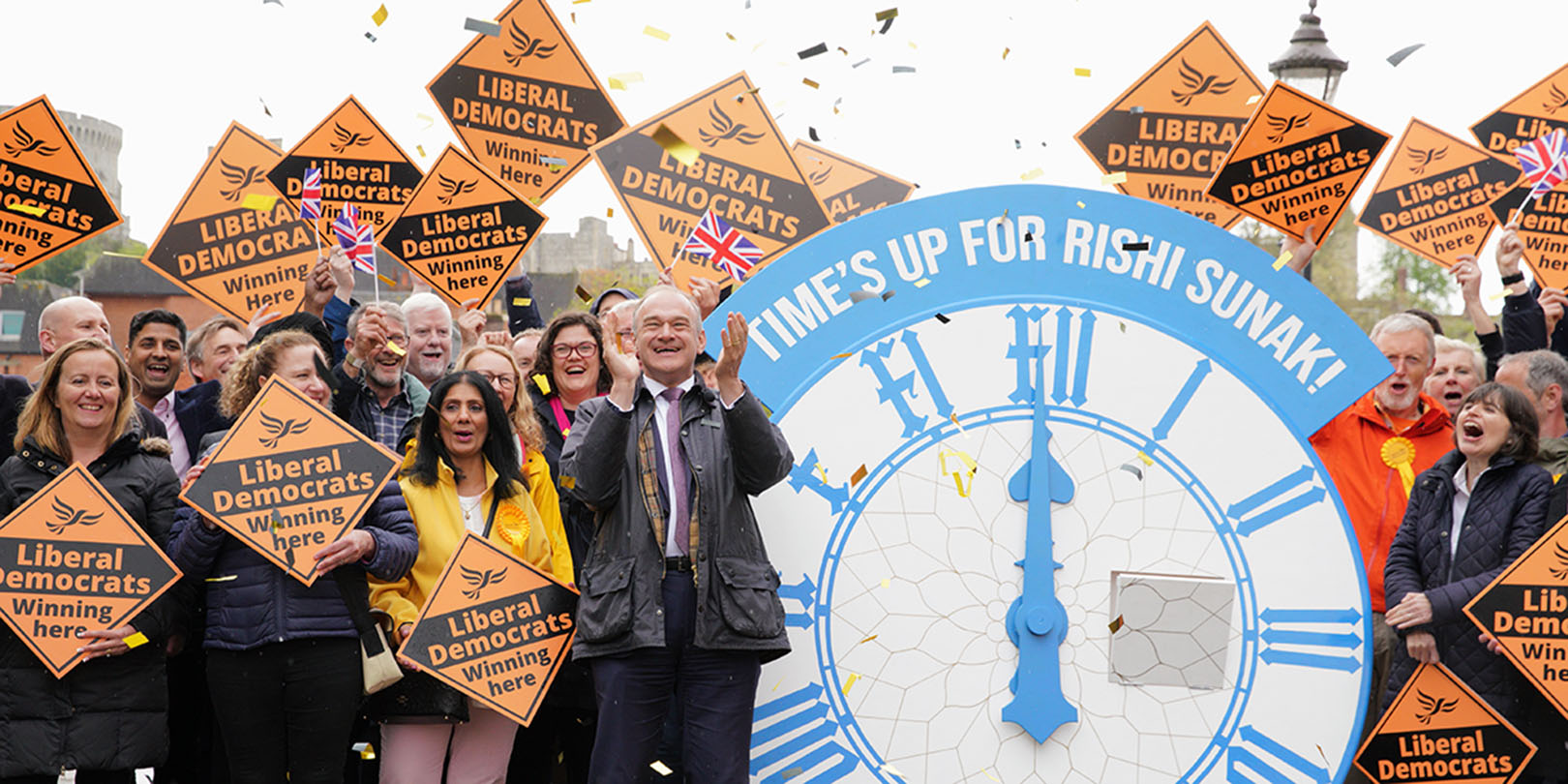 Ed Davey MP and Lib Dem supporters celebrate the 2023 Local Election results with confetti and a giant clock reading, 'Time's up for Rishi Sunak!'