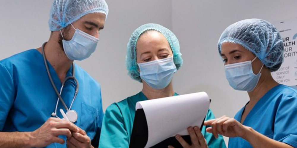 3 doctors look at a clipboard together.