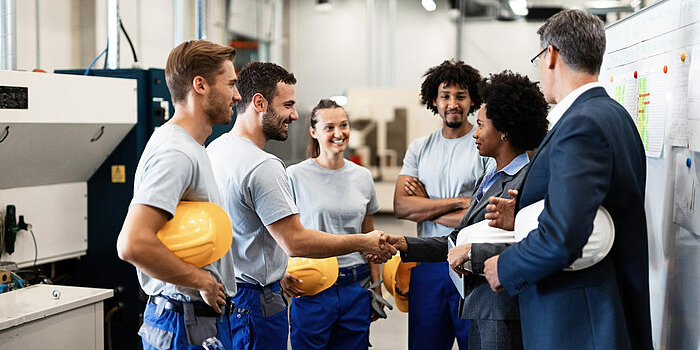 Factory workers meeting business people.
