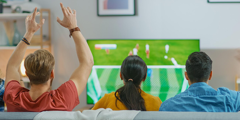 Friends watching sport together on the sofa.