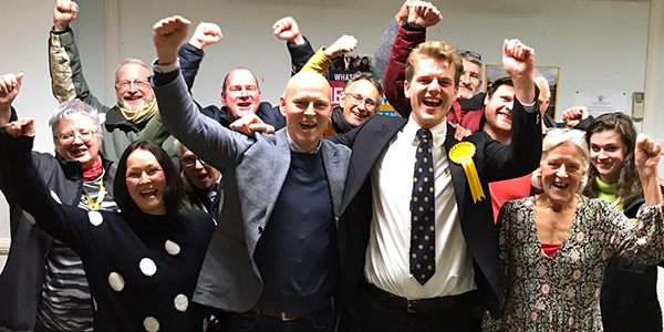 A group of Liberal Democrats celebrate with their arms in the air